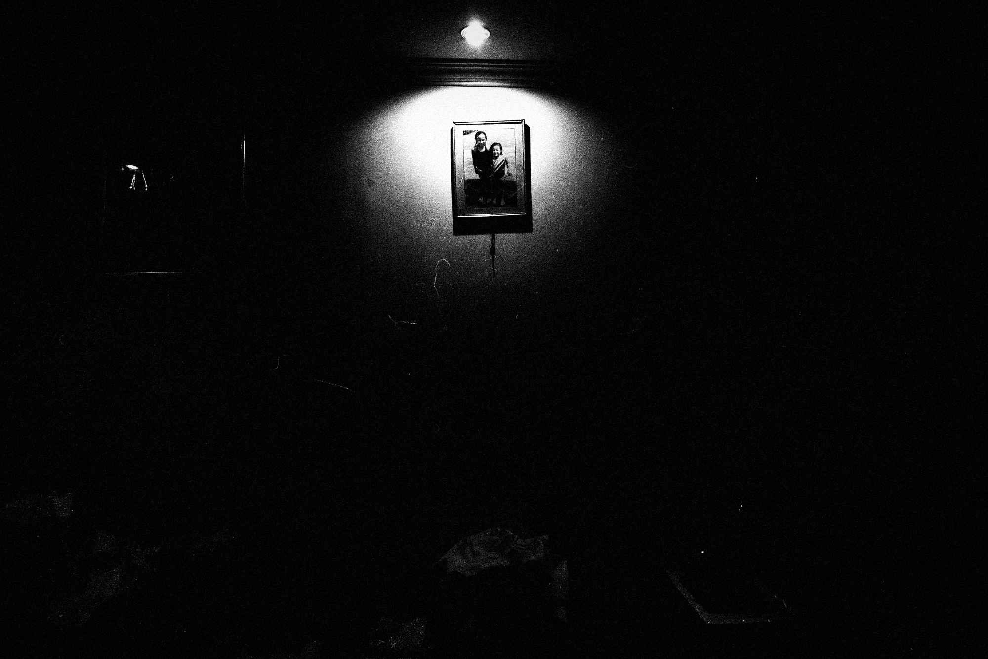 El retrato de Zuka en la pared, iluminado bajo una lámpara solitaria
