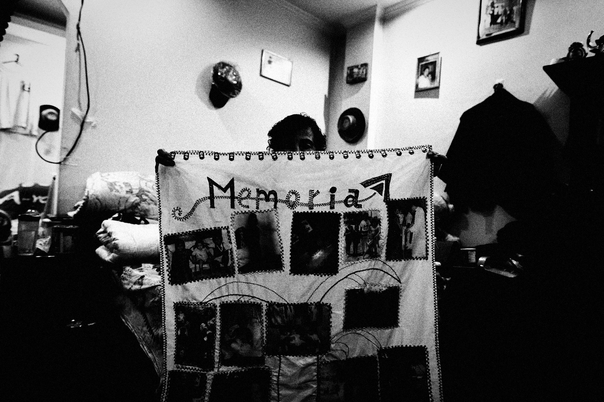 Blanca sostiene el tapiz Memoria con fotos de su hija